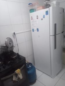 Una cocina con estufa y refrigerador blanco. en Quarto no Rio Vermelho laranja, en Salvador