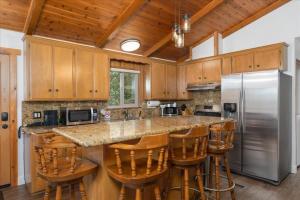 a kitchen with wooden cabinets and a large island with bar stools at Evergreen in Wawona +18 photos