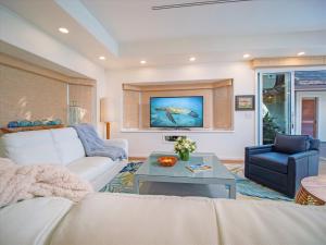 ein Wohnzimmer mit einer weißen Couch und einem Tisch in der Unterkunft Remodeled Beachfront Estate, Magnificent Mango Surf in Kihei