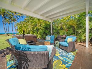 eine Außenterrasse mit Stühlen und einem Tisch mit Blick auf das Meer in der Unterkunft Remodeled Beachfront Estate, Magnificent Mango Surf in Kihei
