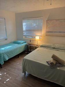 a bedroom with two beds and a table with a lamp at La Mare Fort Lauderdale Airport in Fort Lauderdale