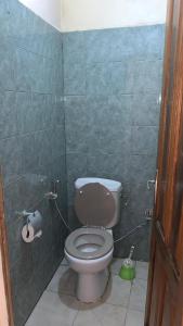 baño con aseo y pared de azulejos verdes en Sen Luxe Immo, en Darou Rhamane