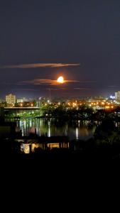 a full moon rising over a city at night at ALTOS DEL MIRADOR b in Patagones