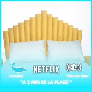 a bed with a wooden headboard and two pillows at Le Martil Plage wifi Fibre in Martil