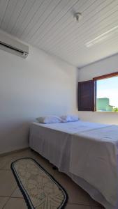 a white bedroom with a bed with a window at Recanto Ebenézer in Taipu