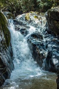 a stream of water rushing down a rocky waterfall at ANCESTRAL GLAMPING in Barbosa