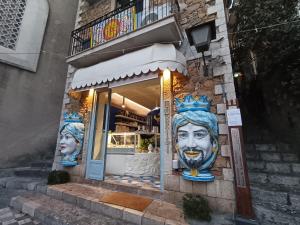 a building with a store with statues of faces on it at Casa Angioletta in Taormina