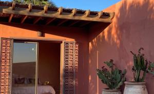 a house with two potted plants in front of a mirror at Kasbah Oum Rabia in Boulaouane