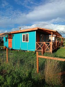 a blue house in a field next to a fence at Cabañas Manolo in Osorno