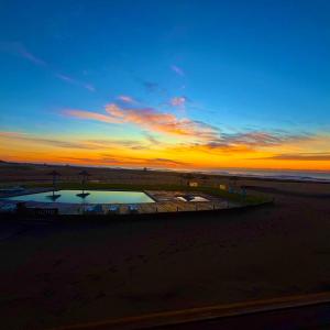 a sunset at the beach with a pool in the sand at Chacras del Mar 4x4 in Mar Azul