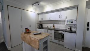 a kitchen with white cabinets and a wooden counter top at City Apartment 2xfree parking - Pool - Gym Wi-Fi in Perth