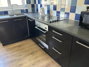 a kitchen with black cabinets and a sink at Daisy Cottage in Lymington