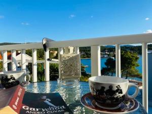 a table with two cups and a book on a balcony at Apartments by the sea Loviste, Peljesac - 24163 in Lovište