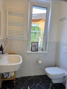 a bathroom with a sink and a toilet and a window at Design-Apartments I Klimaanlage I Boxspring I Nespresso I Parklplatz in Weil am Rhein +56 photos