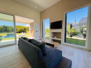- un salon avec un canapé, une télévision et de grandes fenêtres dans l'établissement Costa Esmeralda 4 Dorm,4 Baños,10 perso, pileta, à Costa Esmeralda