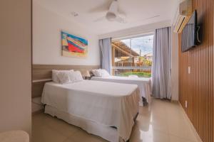 a hotel room with two beds and a window at GUARAJUBA Condomínio PARAÍSO DOS CORAIS BEACH RESORT 132 in Guarajuba +76 photos