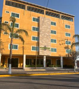 a large orange building with palm trees in front of it at ABERDEEN HOTEL DOLORES HIDALGO in Dolores Hidalgo