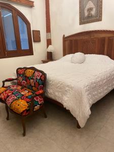 a bedroom with a large bed and a chair at Casa del León in Oaxaca City