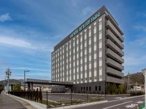 a large building with a sign on top of it at Hotel Route Inn Okayama Ibara in Ibara