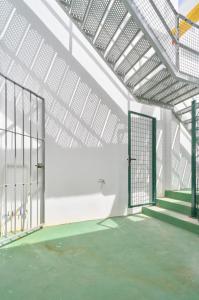 a tennis court with a gate in a white building at Hasta para 6 viajeros, Luz Natural Cocina Equipada in Algeciras