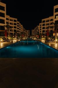 une grande piscine la nuit avec de grands immeubles dans l'établissement Bright and Airy Chalet Near the Beach, à Port-Saïd