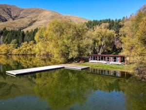 a house on the shore of a body of water at Blue Mountain Lake Lodge and Lake House Fairlie in Fairlie
