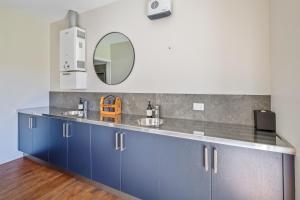 a bathroom with blue cabinets and a mirror at Blue Mountain Lake Lodge and Lake House Fairlie in Fairlie