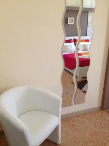 a living room with a white chair and a mirror at Don Mico 'Case Vacanze' in Riposto