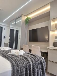 1 Schlafzimmer mit einem großen Bett mit 2 Stühlen und einem TV in der Unterkunft Beach Haus #23 - Flat de luxo com terraço in João Pessoa