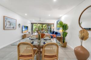 a dining room and living room with a table and chairs at Temple Breeze - Swim Out Apartment in Port Douglas +40 photos