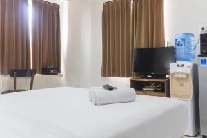 a hotel room with a bed and a tv at Cozy Studio at Elvis Tower Apartment By Travelio in Cikarang