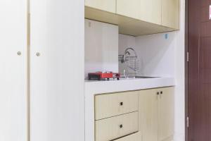 a kitchen with white cabinets and a red appliance at Cozy Studio at Elvis Tower Apartment By Travelio in Cikarang +7 photos