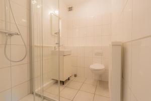 a white bathroom with a shower and a toilet at Wohnung-D-306 in Böhl +5 photos