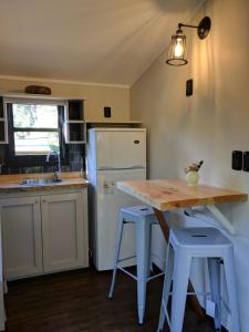 una cucina con un frigorifero bianco, un tavolo e degli sgabelli di Hermosa Cabaña confortable y muy equipada a Santa Ana