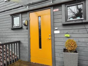 Una puerta naranja en una casa gris con una ventana. en Brattbakken, en Mandal
