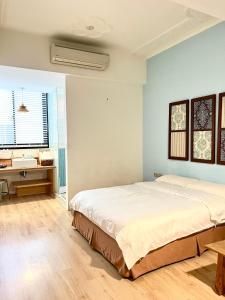 a bedroom with a large bed and a desk at Hour Roots in Tainan
