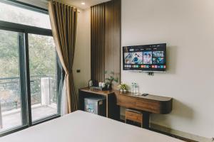 a bedroom with a bed and a desk and a television at Tam Coc Harbor Hotel & Travel By ANMS GROUP in Ninh Binh