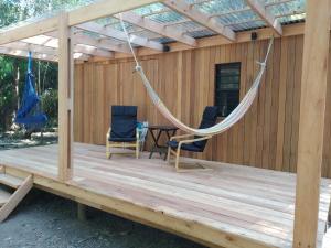 a porch with a hammock and chairs on a deck at Hermosa Cabaña tinny cálida y muy equipada in Santa Ana