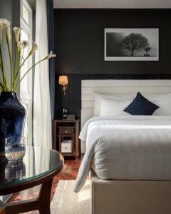 a bedroom with a white bed and a glass table at Kin Hotel Đông Du in Ho Chi Minh City