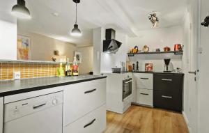 a large kitchen with white cabinets and black appliances at 3 Bedroom Awesome Home In Faaborg in Fåborg