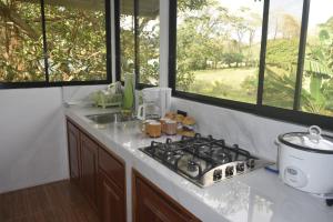 a kitchen with a stove and a sink and windows at Coconut Lodge Maluhia in Pavones