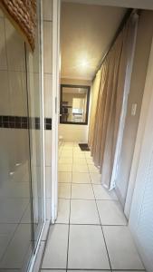 a hallway with a tile floor and a mirror at Artzys Studio in Northriding