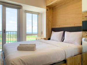 Un dormitorio con una cama grande con una ventana grande. en Minimalist Studio Room at Tokyo Riverside PIK 2 Apartment By Travelio, en Rawalembang