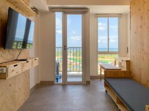 Una sala de estar con televisión y balcón. en Minimalist Studio Room at Tokyo Riverside PIK 2 Apartment By Travelio, en Rawalembang