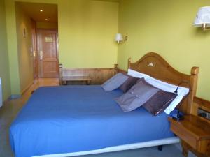 a bedroom with a blue bed with a wooden headboard at Petit Hotel in Pas de la Casa