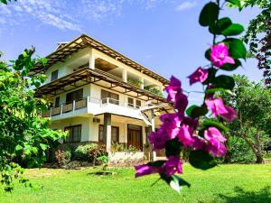 a house with pink flowers in front of it at Sandybridge Eco Farm at Relly's Restaurant in Puerto Princesa City