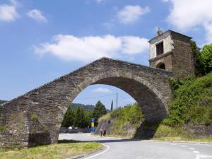 un viejo puente de piedra con una torre en una colina en Pons Minea, en Portomarín