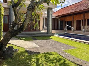 a house with a tree and a swimming pool at Accessible Penyaringan in Sanur