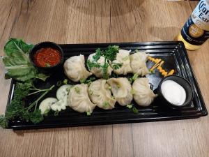 a black plate of dumplings on a table at Alpine Stays Riverside in Jibhi +47 photos