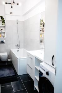 a white bathroom with a tub and a sink at Unirea Towers Deluxe Apartment Modern & Chic in Iaşi +17 photos